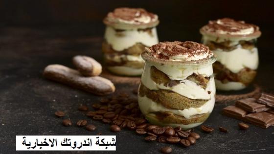 Traditional italian dessert tiramisu with chocolate sauce in a vintage glass jars on a dark rustic slate, stone or concrete background.